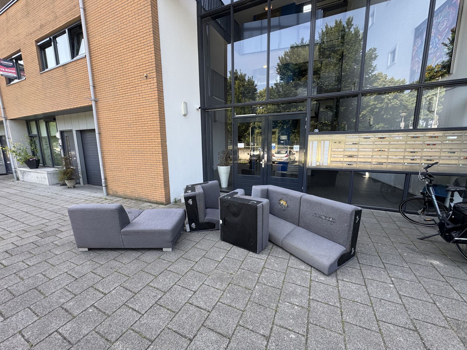 Twee monteurs van MeubelsLatenOphalen.nl dragen een bank naar buiten bij een woning in Amsterdam